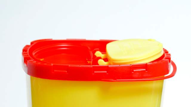 A yellow plastic container with a red lid and a small flap opening on top, on a white background.